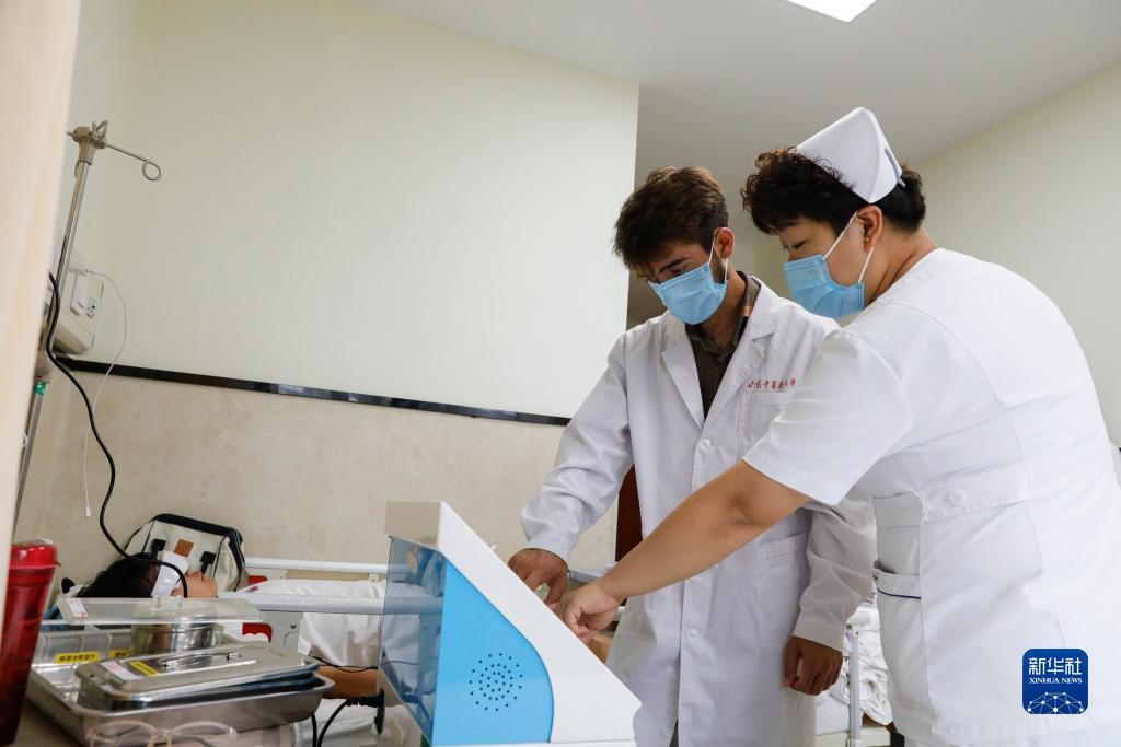 甘肃中医药大学针灸推拿专业的塔吉克斯坦留学生纪明哲（左）在老师的指导下学习直流电离子机器操作（7月27日摄）。新华社记者 陈斌 摄