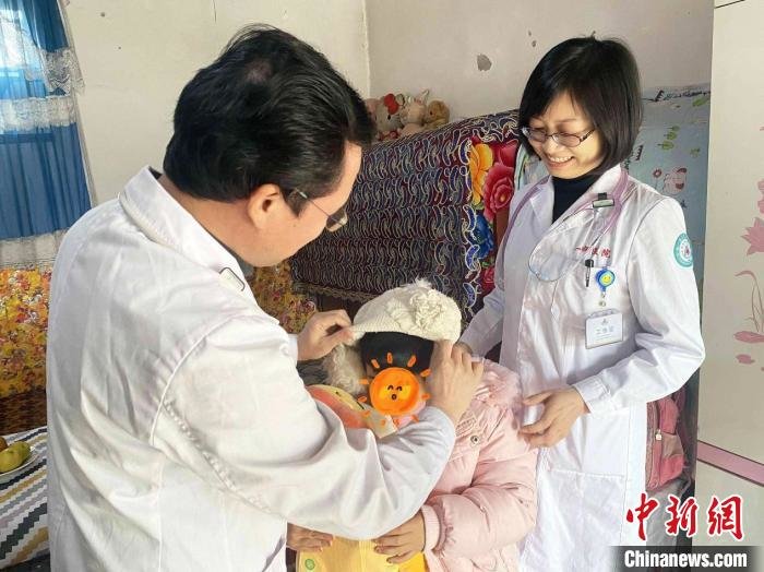 彭克荣给小古丽戴帽子。 周玲玲 摄