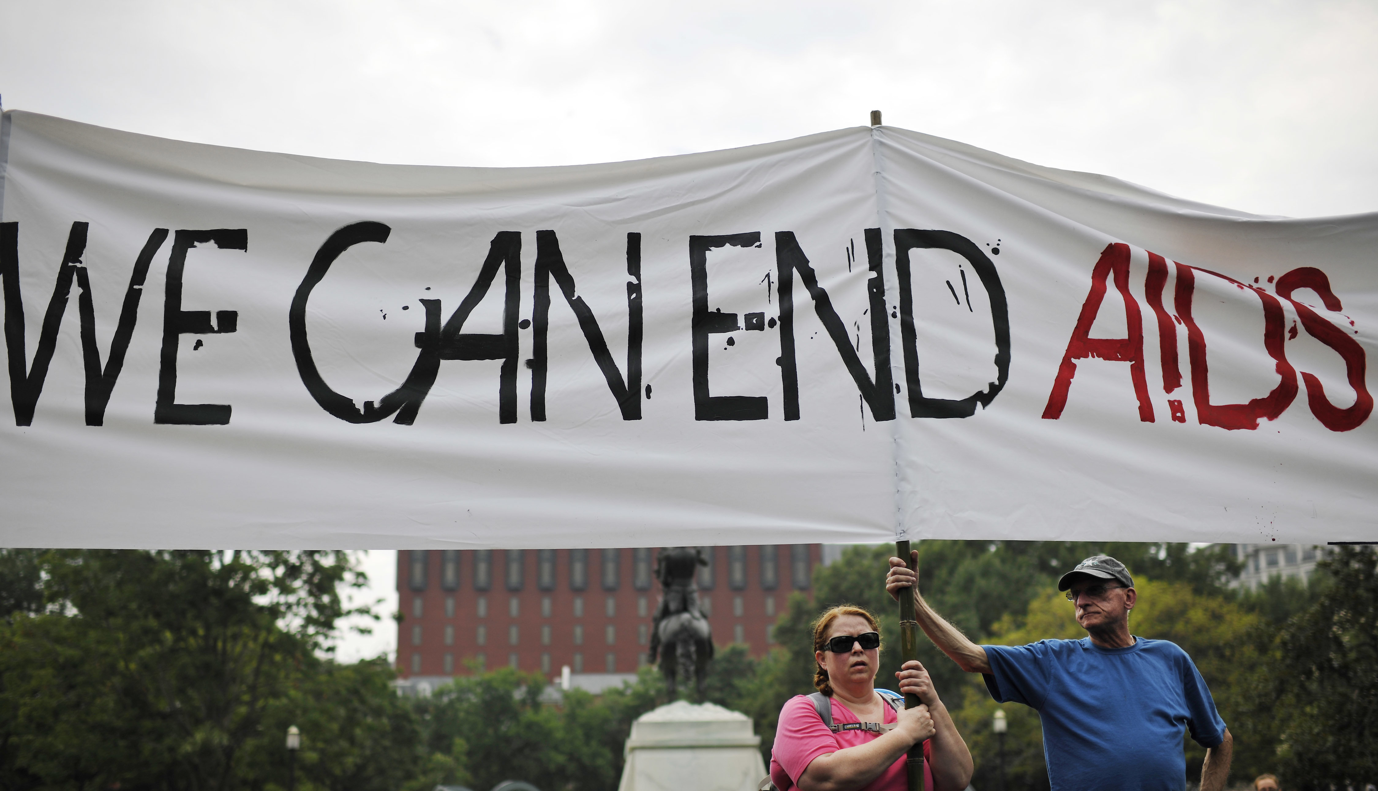 2012年7月24日,在美国首都华盛顿白宫外,人们举起“我们能结束艾滋病”的横幅。新华社记者张军摄
