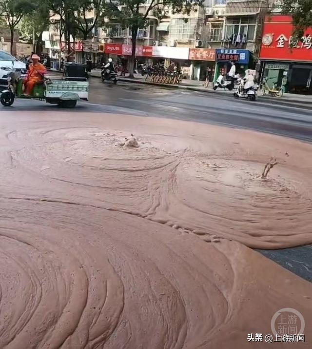 公路中间，持续有红褐色物质从地下喷涌而出。视频截图