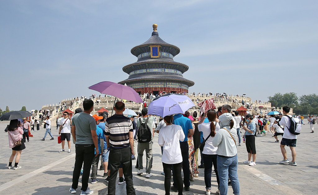 2023年6月18日，北京最高温度达35度，天坛公园内游客打伞遮阳。