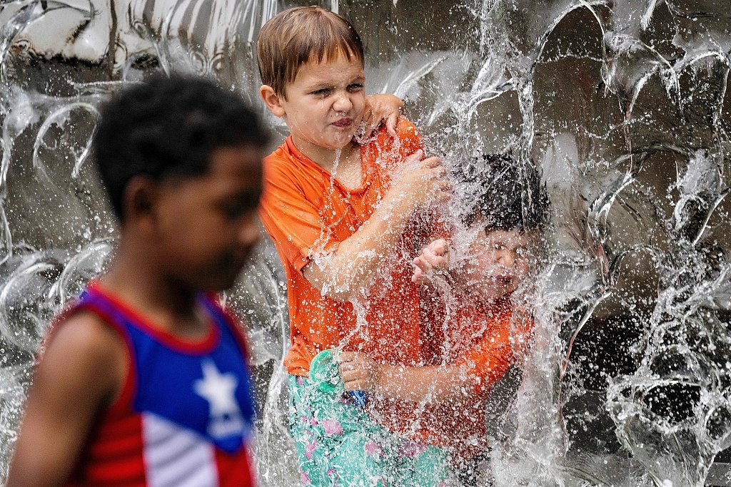 当地时间2023年6月26日，美国华盛顿特区，炎炎夏日，小男孩们在喷泉里玩耍。视觉中国 图