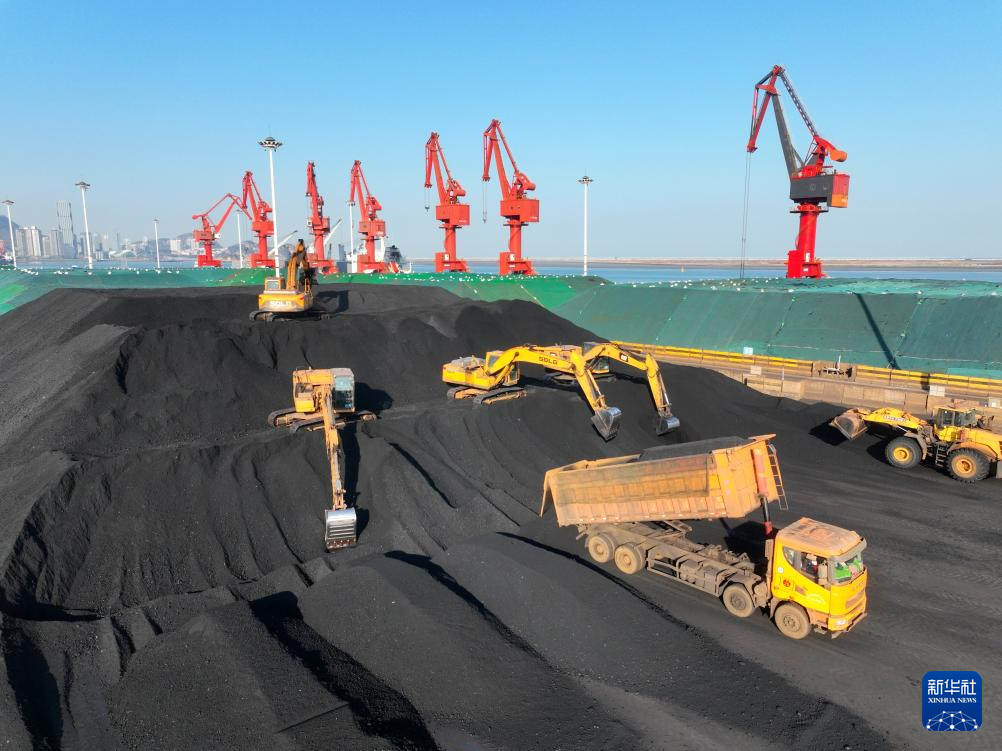 12月23日，在江苏连云港港煤炭码头，大型机械在堆放储存刚从货轮卸运的电煤（无人机照片）。新华社图片