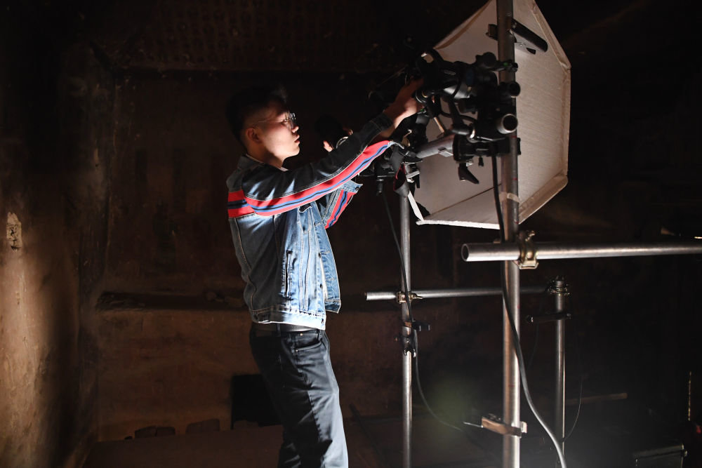 敦煌研究院文物数字化保护团队图像采集人员熊业腾在洞窟内调试设备，准备进行壁画图像采集（4月25日摄）。