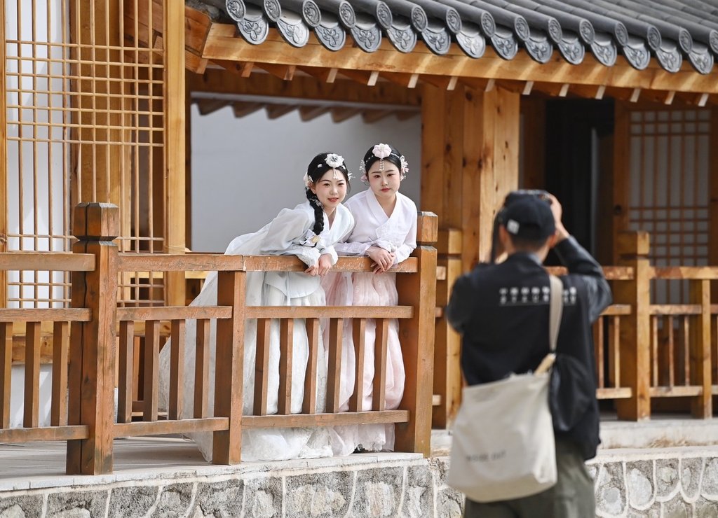 4月13日,在吉林省延边朝鲜族自治州延吉市的中国朝鲜族民俗园内,游客身着朝鲜族服饰拍照留念。吉林省延边朝鲜族自治州是中国最大的朝鲜族聚居地,当地依托特色旅游资源,吸引众多游客来此观光旅游。 中新社记者 张瑶 摄