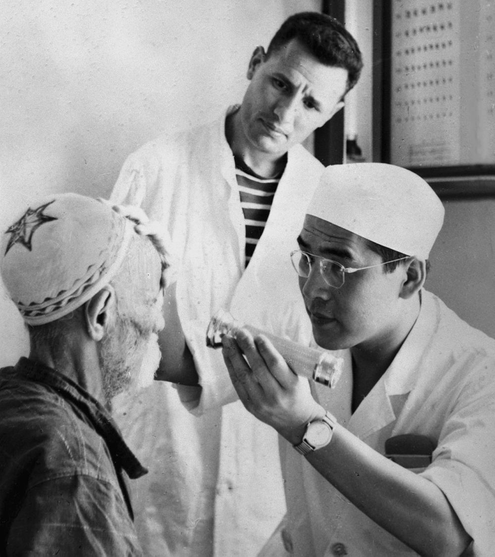 ↑1964年10月，中国医疗队眼科医生刘钢正在阿尔及利亚赛伊达为一白内障患者进行手术前的检查。新华社发（卓上智摄）