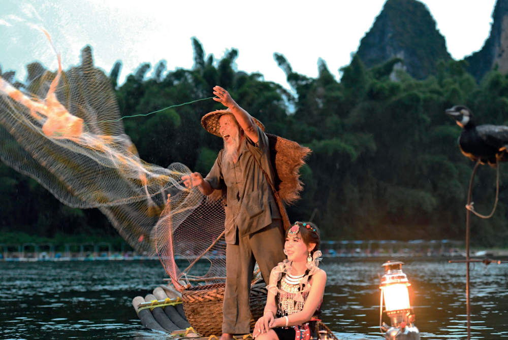 游客在漓江广西阳朔县兴坪镇段的竹筏上体验旅拍(2022年8月25日摄) 周华摄/本刊