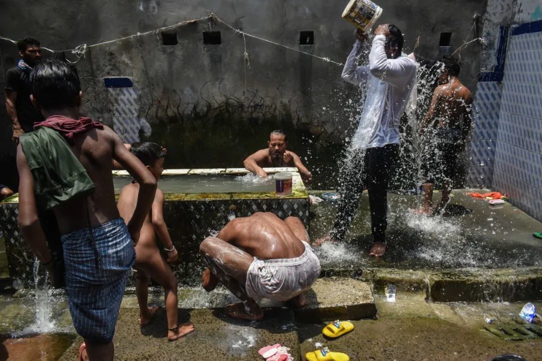 ◆印度加尔各答炎热且潮湿，人们在路边洗澡降温。