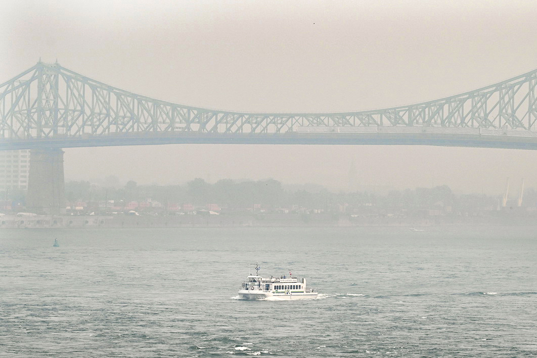 6月25日，加拿大蒙特利尔市，一艘船经过被烟雾笼罩的雅克·卡迪亚大桥，由于森林火灾，该市和该省多个地区发布烟雾警告。