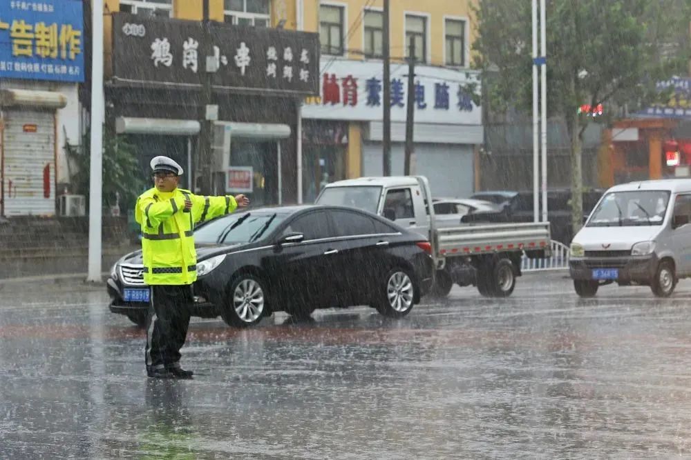 7月31日，在涿州市华阳路与甲秀路十字路口，交警正在雨中指挥交通 / 图源：涿州发布 熊华明 摄
