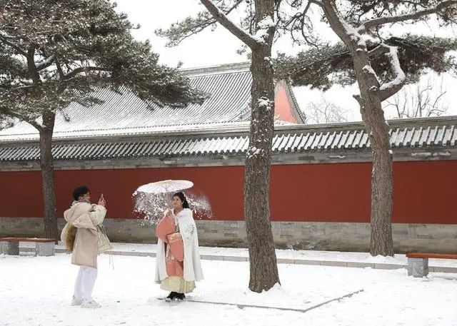 身着汉服打卡故宫等古建筑受到年轻人喜爱，特别是下雪天（图片来源：新华社）