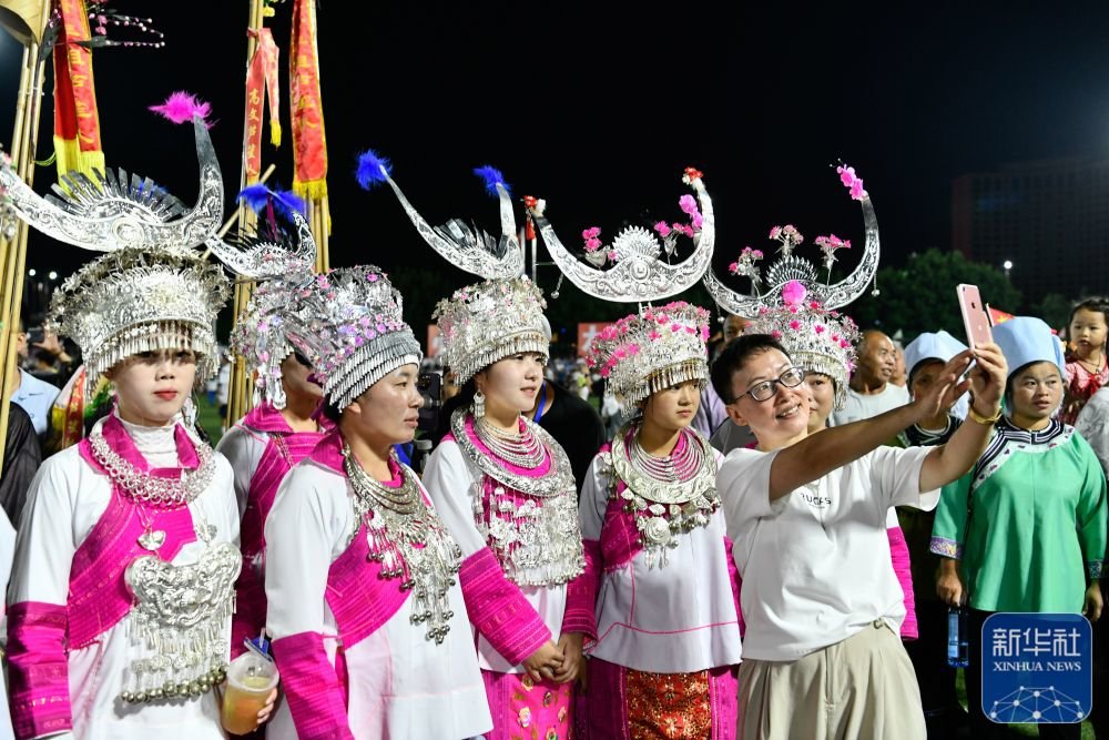 ↑6月9日，一名游客在贵州“村超”足球比赛现场与少数民族拉拉队合影。 新华社记者 杨文斌 摄