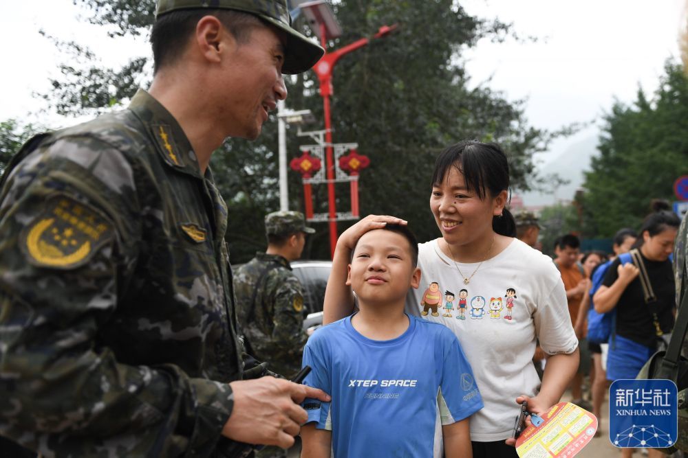 ↑8月2日，在北京市门头沟区妙峰山镇，在乘坐车辆转移前，武天骐（中）与武警北京总队机动三支队的王雷鸣道别。