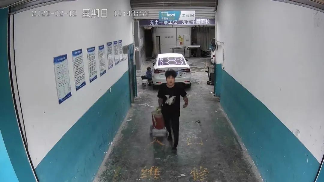 汽车维修店员工快速回到店铺拿大灭火器