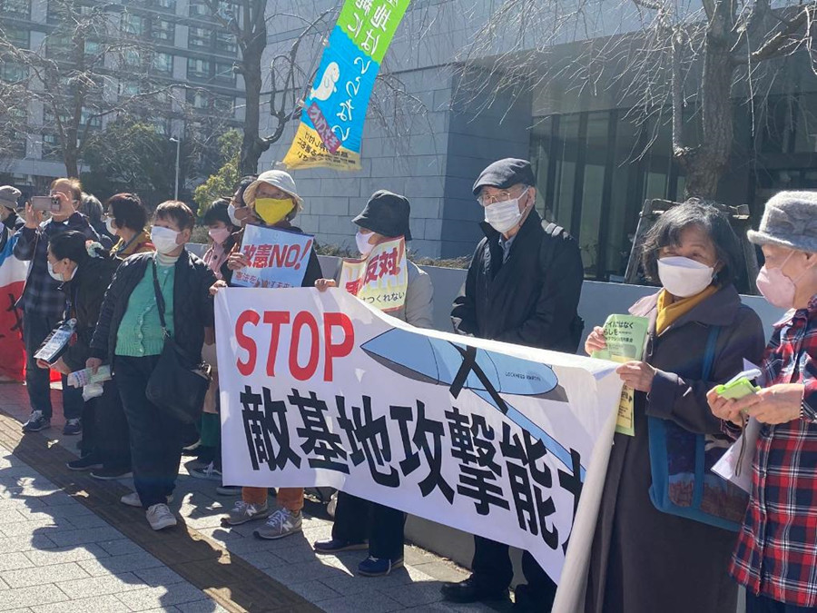 12月28日，在日本东京，日本民众举着标语牌抗议日本众议院通过高额的防卫费预算案。新华社记者郭丹摄