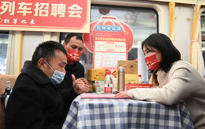 2月6日，在广州开往宁波的K210次列车的餐车上，一位旅客（左一）与企业招聘人员洽谈意向岗位。新华社记者黄宗治 摄
