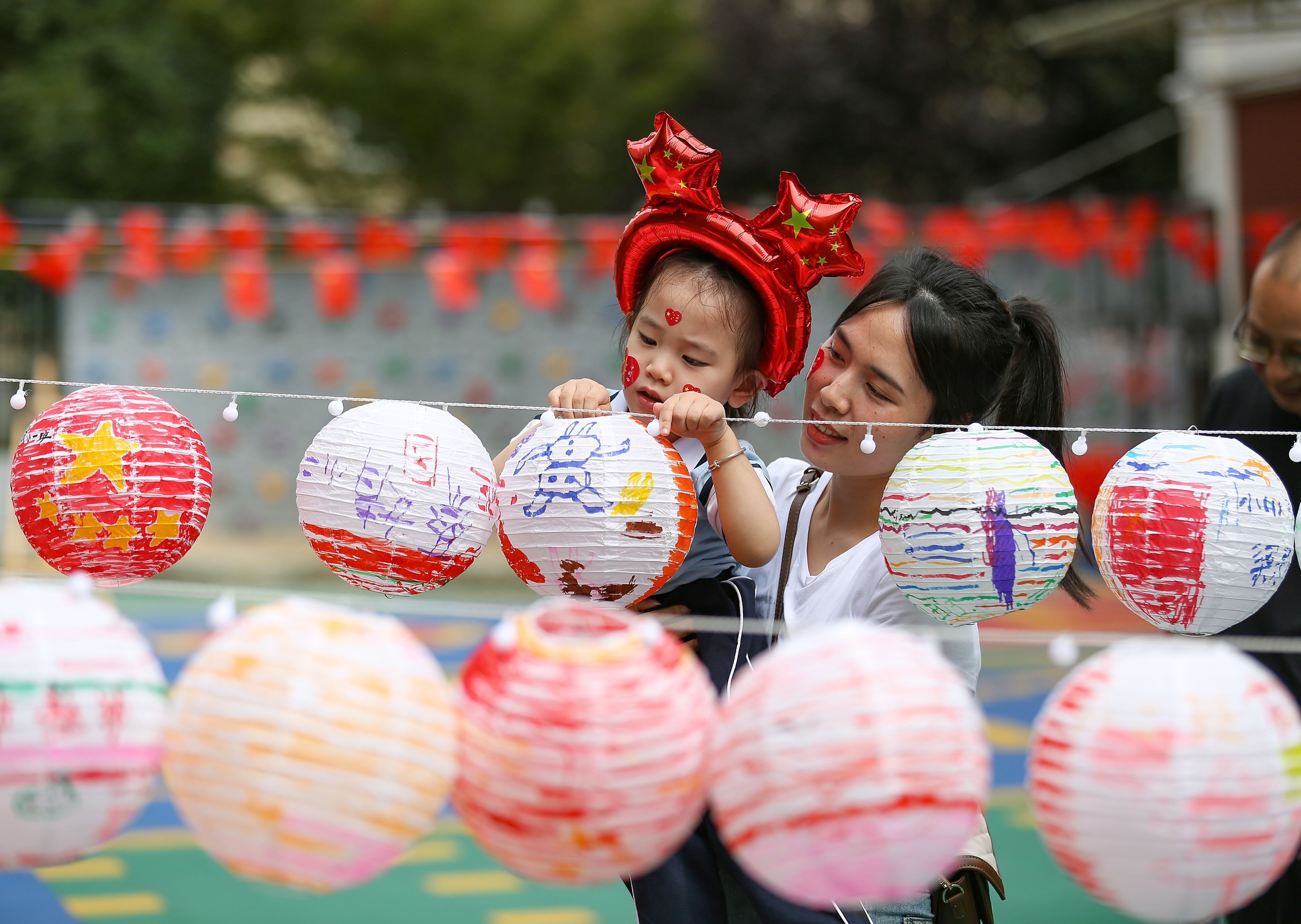 9月27日，貴州省黔東南苗族侗族自治州丹寨縣第三幼兒園的小朋友與家長(zhǎng)在展示共同繪制的中秋燈籠。 澎湃影像 圖