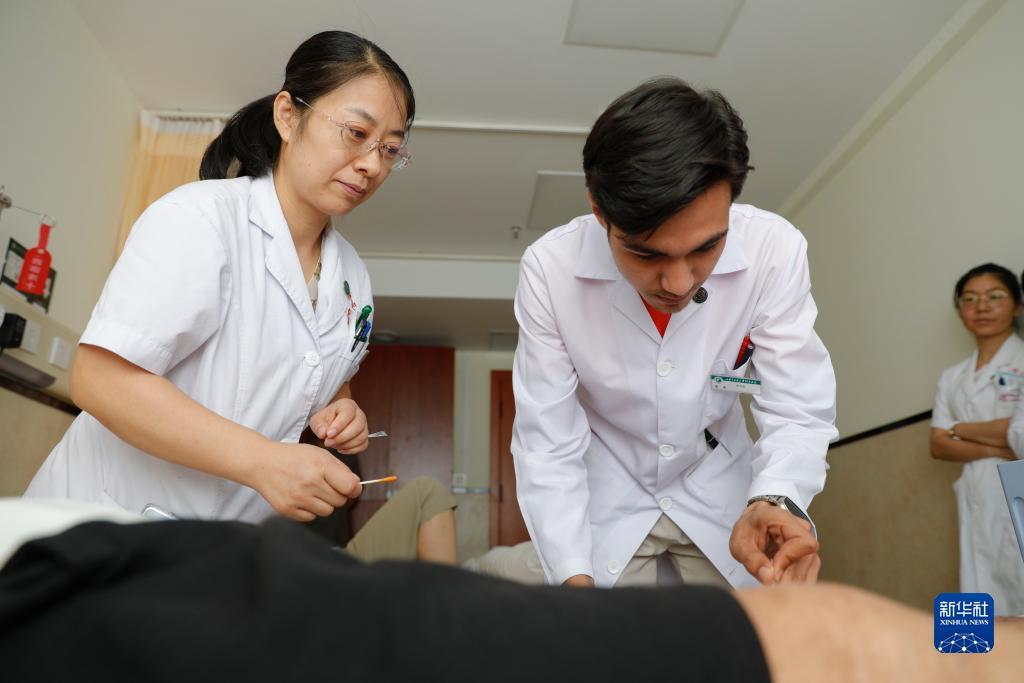 甘肃中医药大学针灸推拿专业的土库曼斯坦留学生迪达（右）在老师指导下为患者进行针刺治疗（7月28日摄）。新华社记者 陈斌 摄