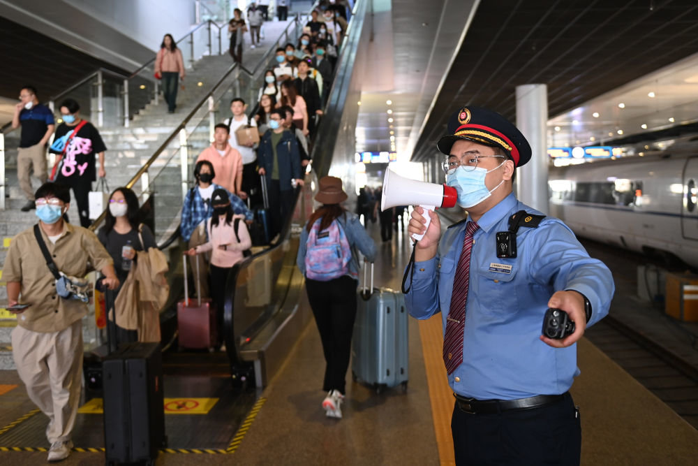 5月1日,在杭州东站站台,客运员张梓绅在引导旅客乘车.