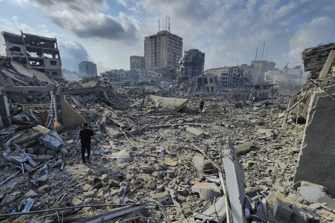 ◆2023年10月10日，巴勒斯坦人走过加沙城被以色列空袭摧毁的建筑物废墟。