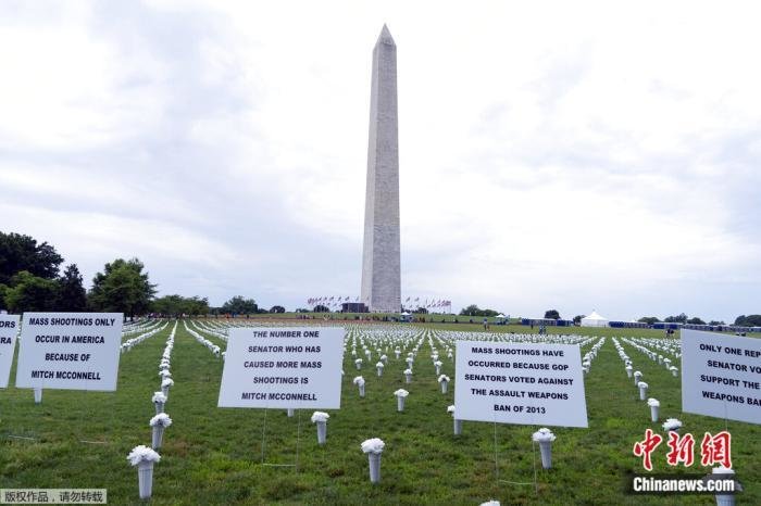 资料图：2022年6月11日，在美国华盛顿纪念碑前举行的“为我们的生命游行”集会期间，人们在枪支暴力纪念设施上放置标志牌，以支持枪支管制。