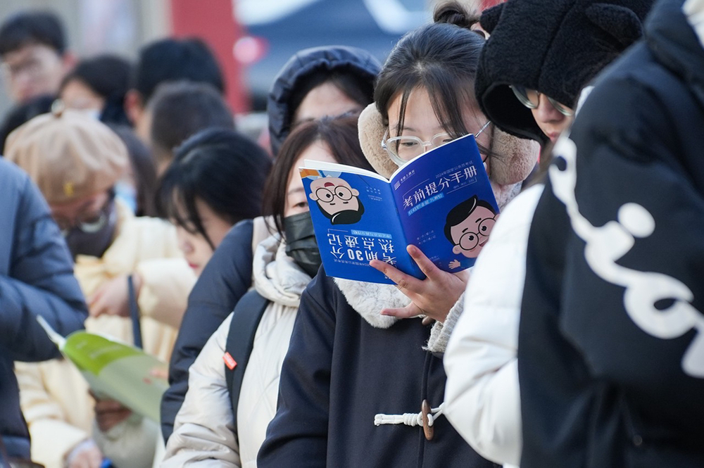 2023年11月26日，山西省太原市，考生在考场外复习。当日，中央机关及其直属机构2024年度考试录用公务员公共科目笔试举行。 中新社记者 武俊杰 摄