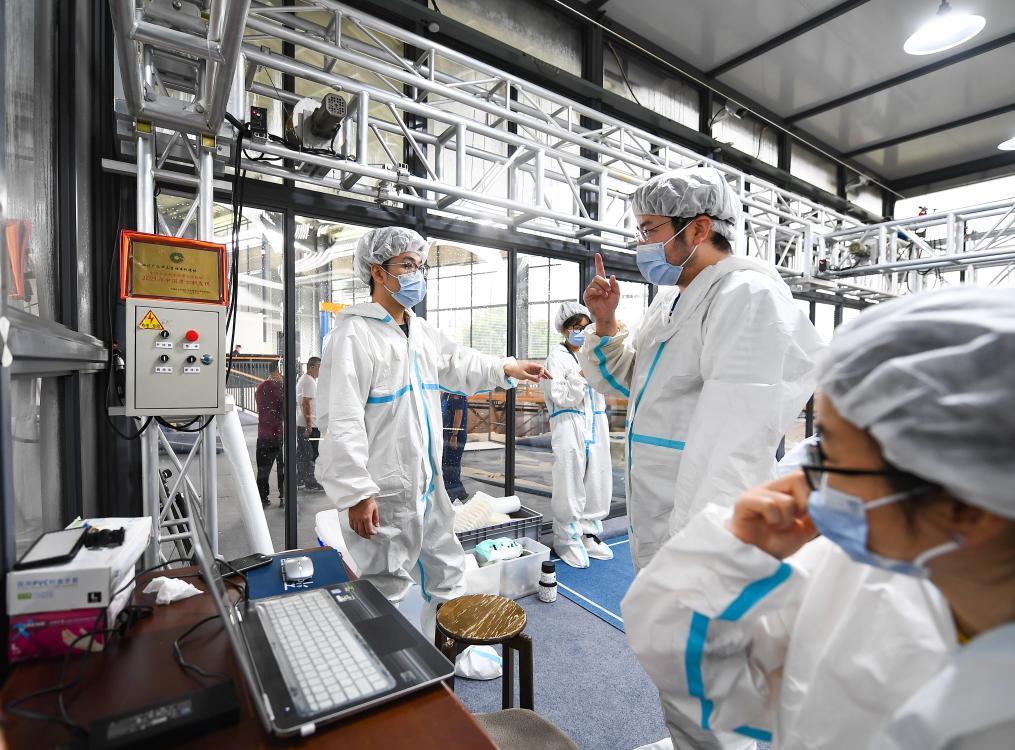 在四川省广汉市三星堆遗址8号“祭祀坑”,考古队工作人员在恒温恒湿的考古“方舱”内交流(2022年6月1日摄)。新华社记者 王曦 摄