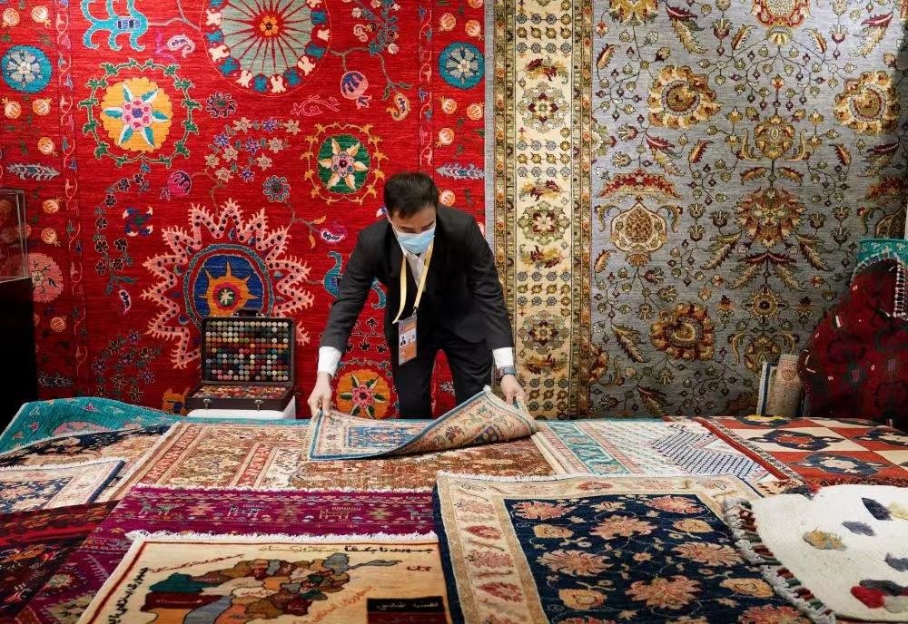 △2021年11月8日，工作人员在进博会阿富汗手工羊毛地毯展台整理商品。