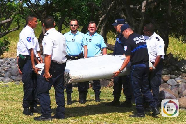 在法属留尼汪岛，警察搬运一块疑似马航MH370客机的残骸。 （新华社/路透）
