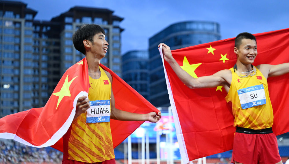 8月3日，中国选手黄华锋（左）和粟文在成都第31届世界大学生夏季运动会田径项目男子三级跳远决赛后庆祝。黄华锋以16米76的成绩获得季军。新华社记者 邓华 摄