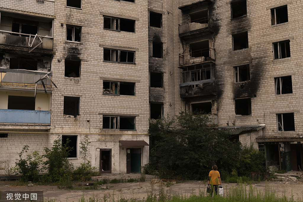 当地时间2023年8月2日，乌克兰博罗江卡，一名妇女停下来查看一栋在俄罗斯袭击中严重受损的公寓楼。（视觉中国）