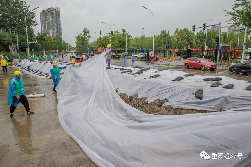 7月30日上午，北京通州区紫运西路，工人正在添加防雨布加固堤坝。新京报记者王子诚 摄