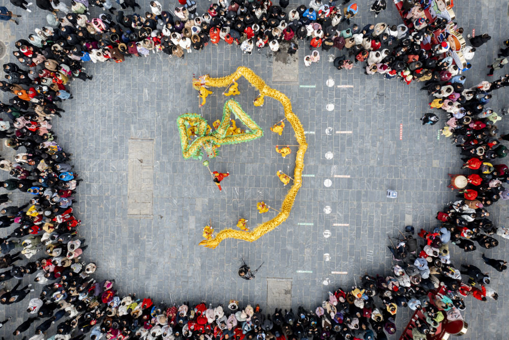 ↑1月24日，民俗表演队伍在安徽省合肥市肥西县三河古镇的“民间文化艺术节”活动上表演舞龙（无人机照片）。新华社发（徐勇 摄）