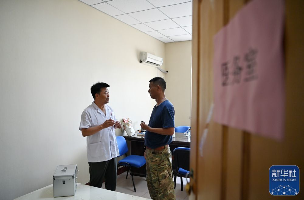 8月4日，郝庆水（右）在第六埠村安置点内的医务室和医生交流。