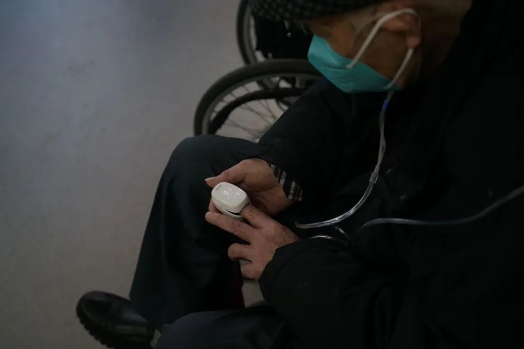 2022年12月27日,北京丰台,一名老人一边在医院急诊室吸氧,一边用指氧仪自测血氧饱和度,指氧仪显示,他当时的血氧饱和度为91%。中青报·中青网记者 李强/摄