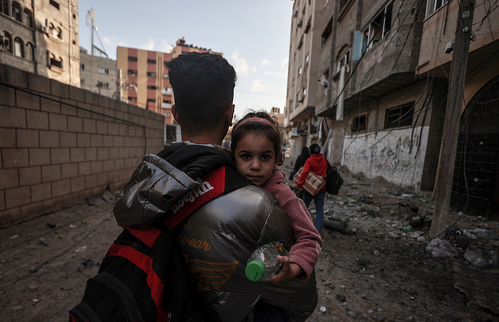 当地时间2023年10月16日，以色列轰炸加沙后，人们带着孩子逃离家园。