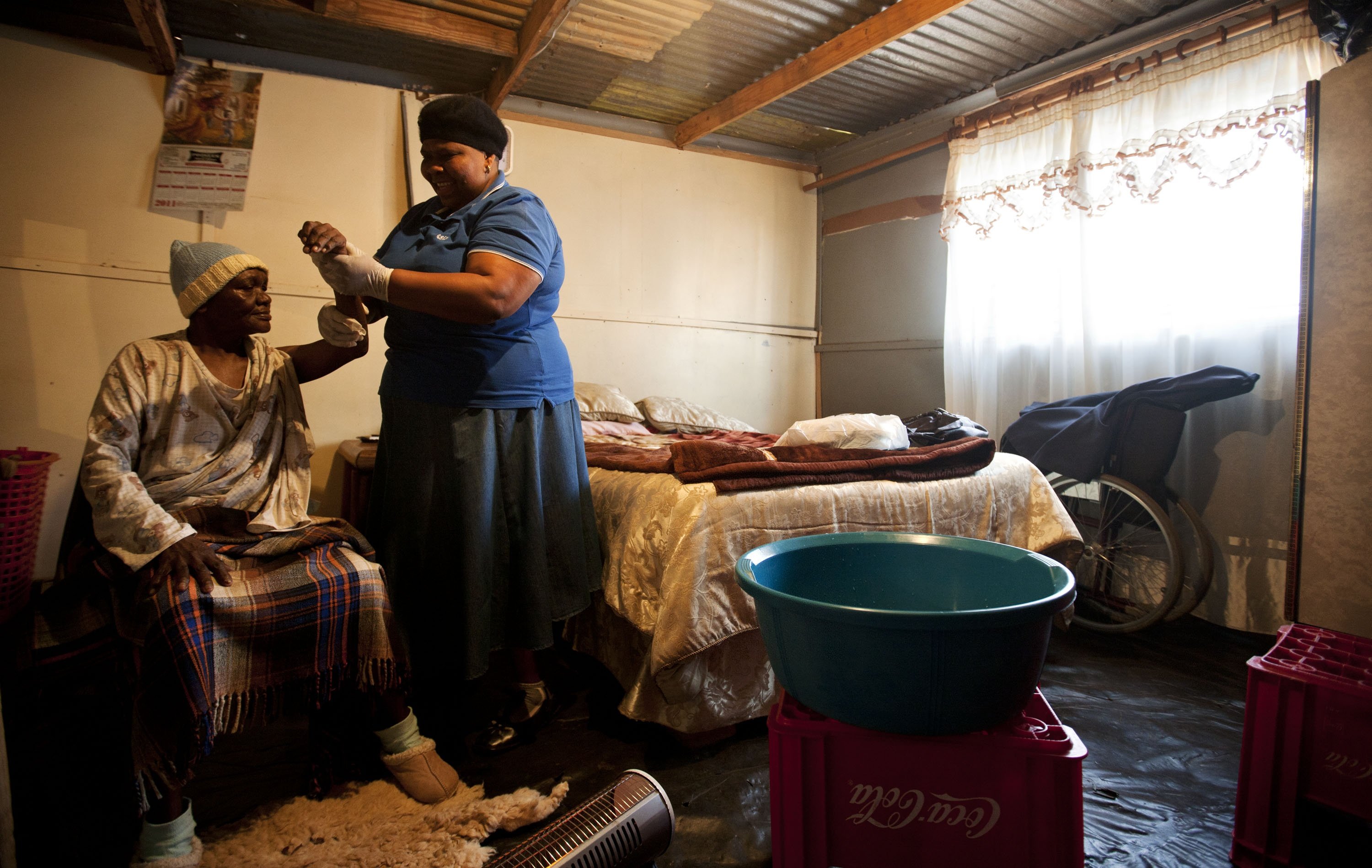 2011年8月23日,在南非约翰内斯堡以南约45公里的小镇奥兰治农场,志愿者利迪亚·姆巴洛来到64岁的艾滋病患者安娜家中帮助她进行简单的治疗。新华社记者费茂华摄