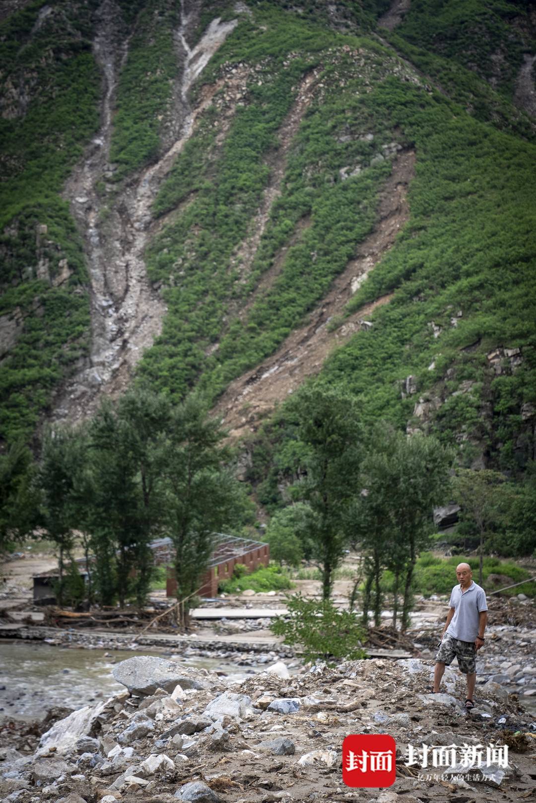 8月5日，隗功龙站在被泥石流冲毁的房屋上。拍摄：杨峰