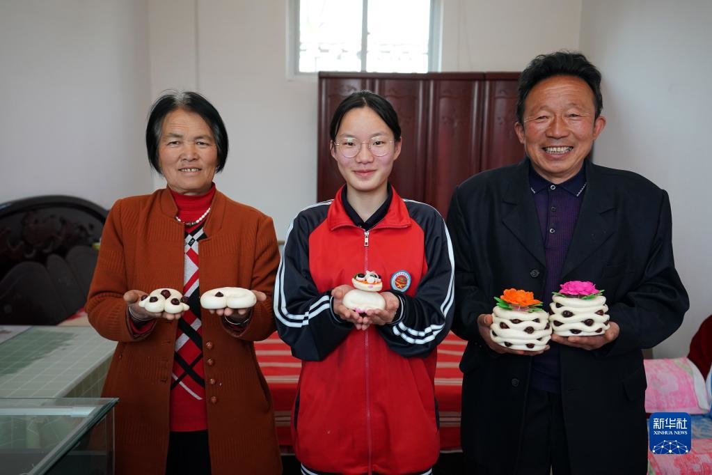 在山西省霍州市师庄乡冯南垣村，师菁悦（中）和爷爷师红兵（右）、奶奶朱海丹（左）在展示年馍（2022年5月14日摄）。新华社记者 詹彦 摄