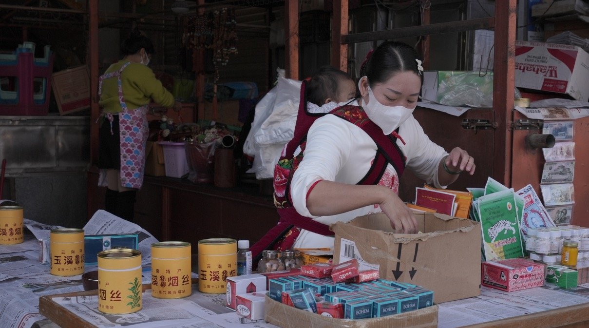 1月8日,王灿准备出摊。王灿和她的朋友姚思思共同照看着一个摊位。2005年,王灿来到瑞丽,靠着在大国门帮人拍游客快照谋生,直到2015年底,租下了这个摊位开始卖一些工艺品。