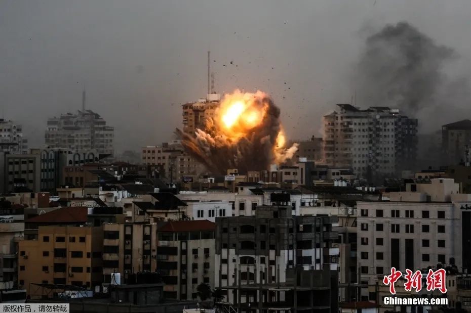 图为当地时间10月9日，以色列空袭期间，加沙地带一栋建筑上空升起浓烟和火球。