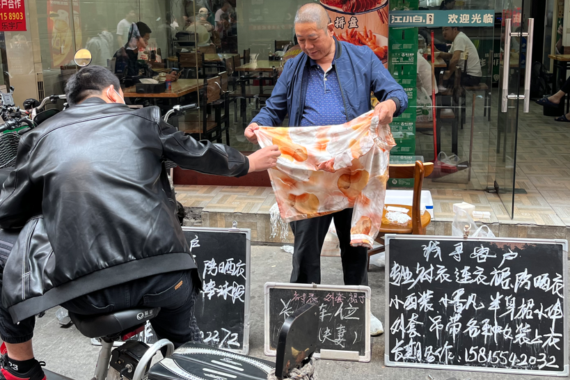 老板拿着样衣等待来往的“零工”挑选