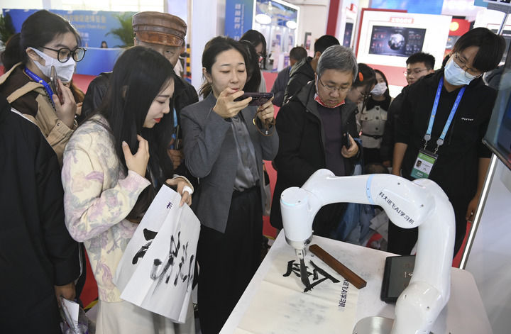 参观者在首届中国国际供应链促进博览会数字科技链展区科大讯飞展位观看一款AI书法机器人写毛笔字（2023年12月2日摄）。新华社记者 蔡湘鑫 摄