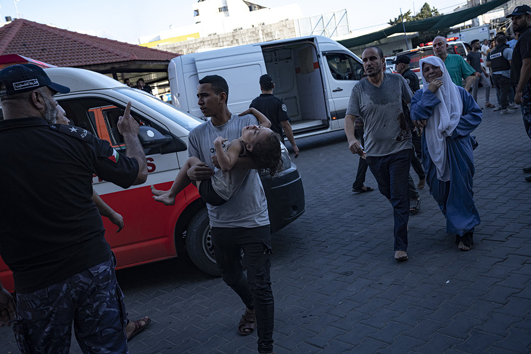 当地时间2023年10月10日，加沙城，一名巴勒斯坦男子抱着一名受伤的女孩进入医院。