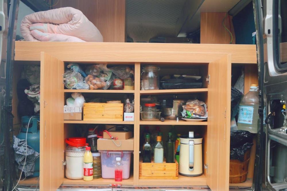打开后车厢,上部分是张瀛的床,下部分是做饭的厨具和调料。朱雅文 摄