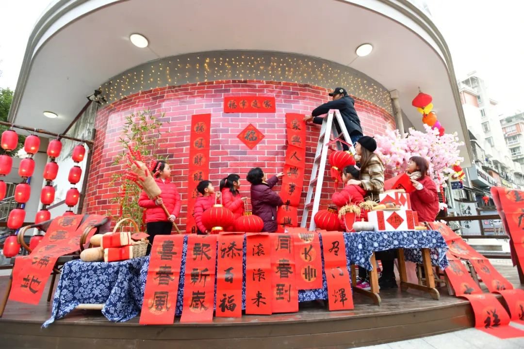 1月21日,在建德新安江街道健安社区,人们在社区大门口贴春联、挂灯笼 图源:新华社