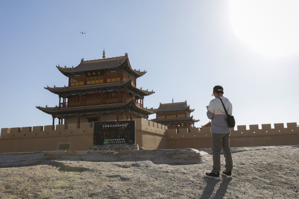 7月14日,嘉峪关丝路(长城)文化研究院文化遗产监测中心负责人张翔在甘肃嘉峪关关城景区使用无人机进行巡查。