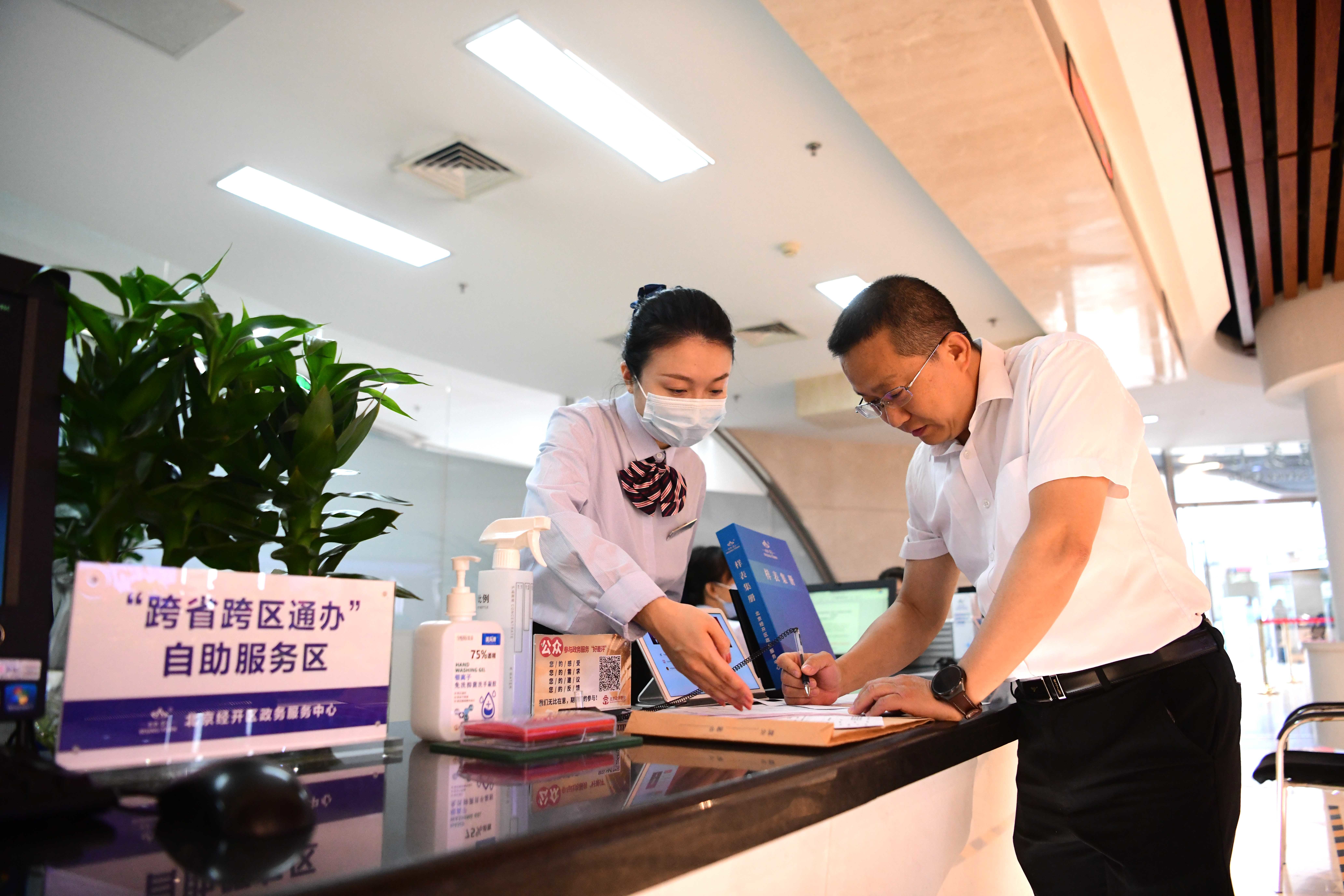 北京经开区政务服务中心“跨省通办”窗口，工作人员正在帮助企业办理跨省业务。 和冠欣摄