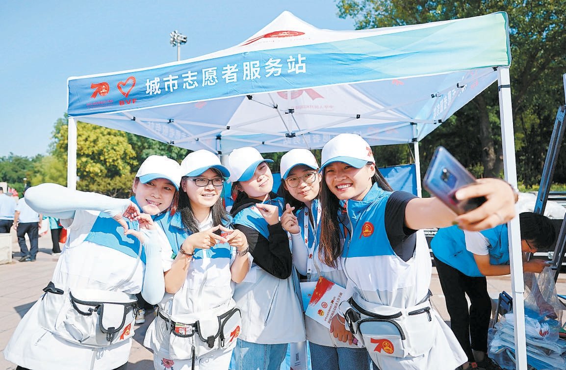 值守在中央电视塔前的庆祝中华人民共和国成立70周年活动志愿者合影留念。 本报记者 方非摄