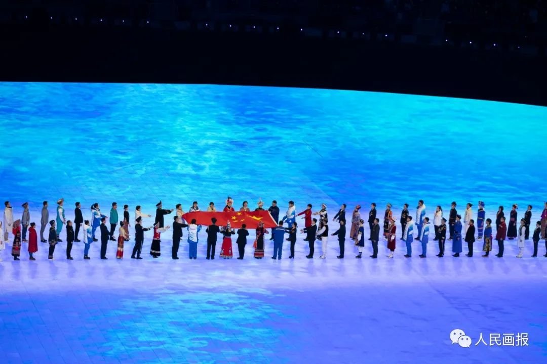 2022年2月4日晚,北京第二十四届冬季奥林匹克运动会开幕式,来自中国各行各业、先进模范人物、56个民族的代表,用双手将五星红旗缓缓传递到体育场升旗区。摄影 陈建/人民画报
